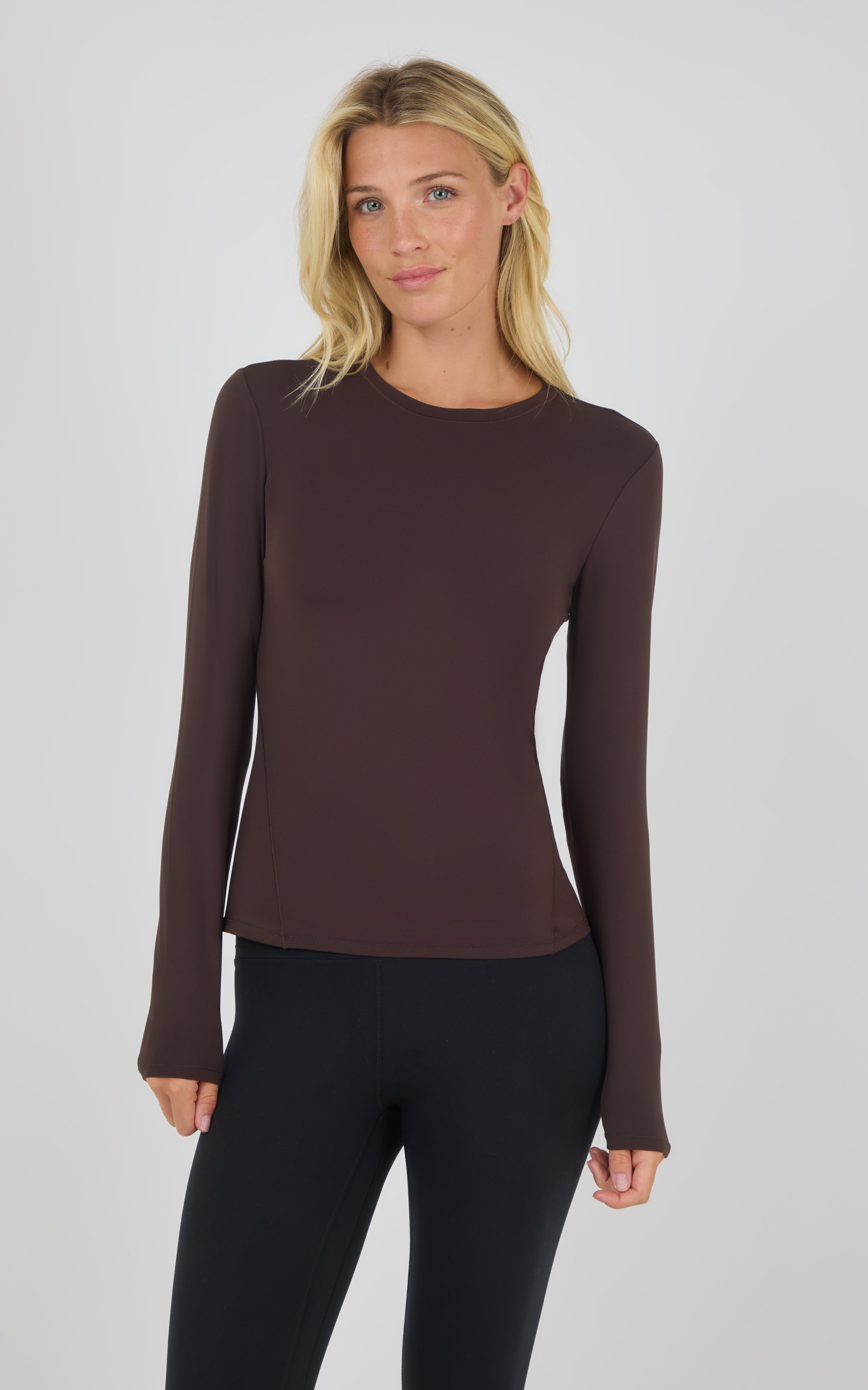 Chocolate brown long sleeve fitted top with crew neck worn with black pants.