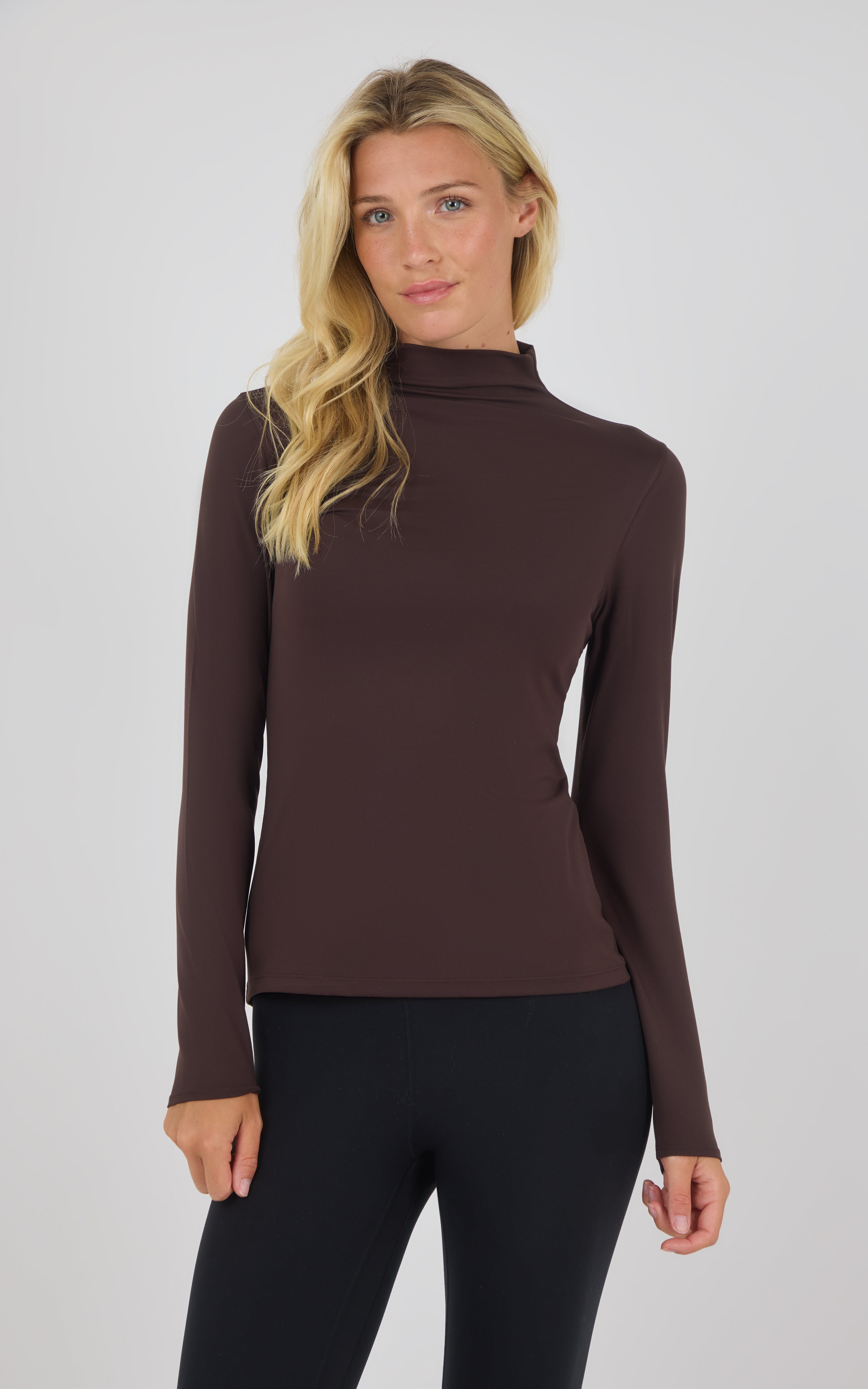 Dark brown mock neck long sleeve top with fitted silhouette on model.