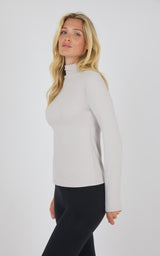 Light gray mock neck long sleeve top on model, slim fit with smooth fabric texture.