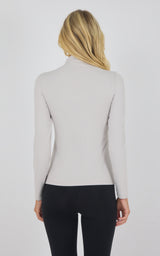 Light beige mock neck long sleeve top with slim fit, worn with black pants, back view.