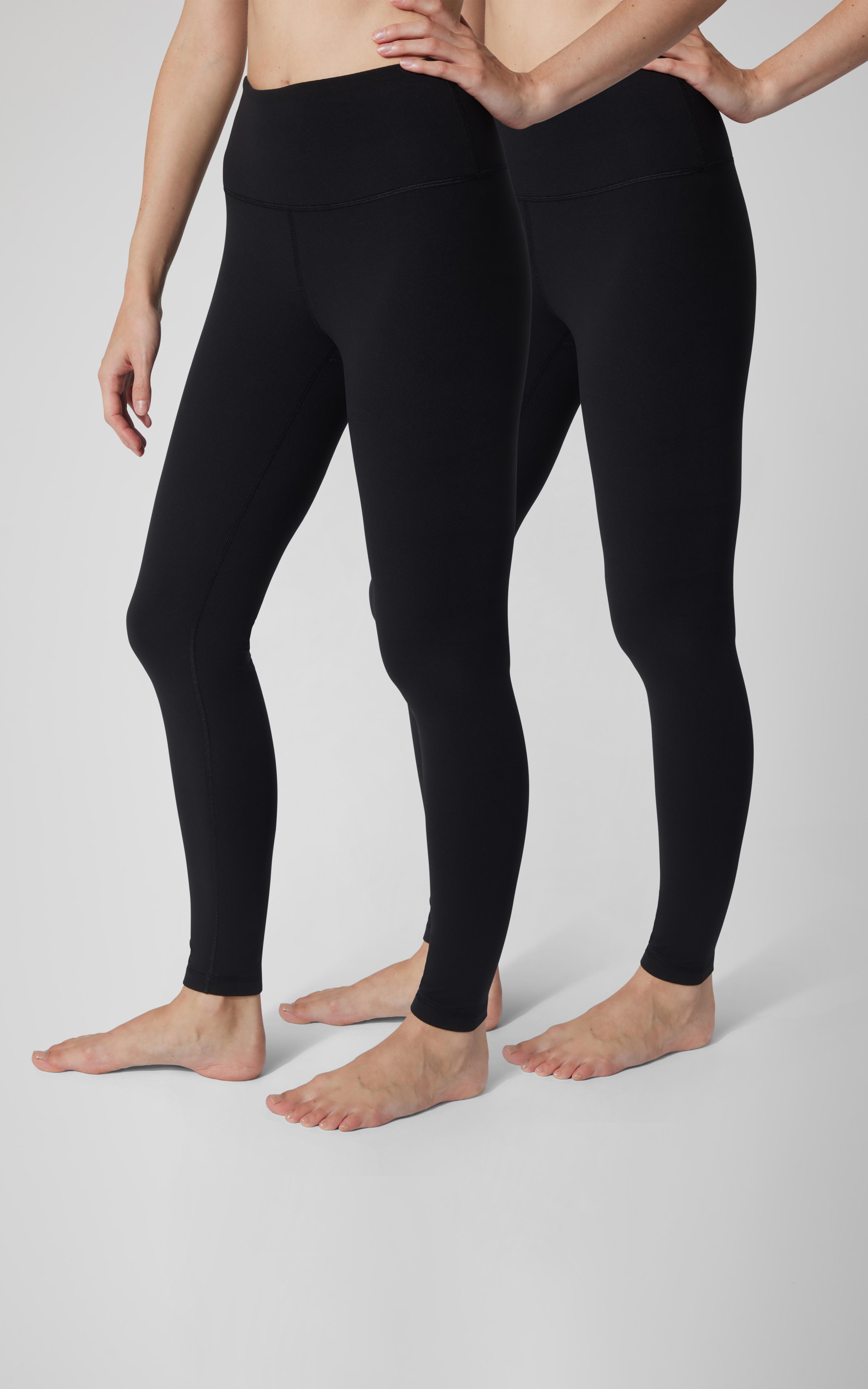 Two models wear black, high-rise full-length leggings with smooth, close-fitting legs and a wide waistband.