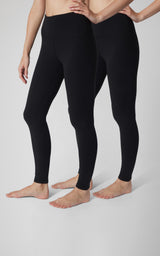 Two models wear black, high-rise full-length leggings with smooth, close-fitting legs and a wide waistband.