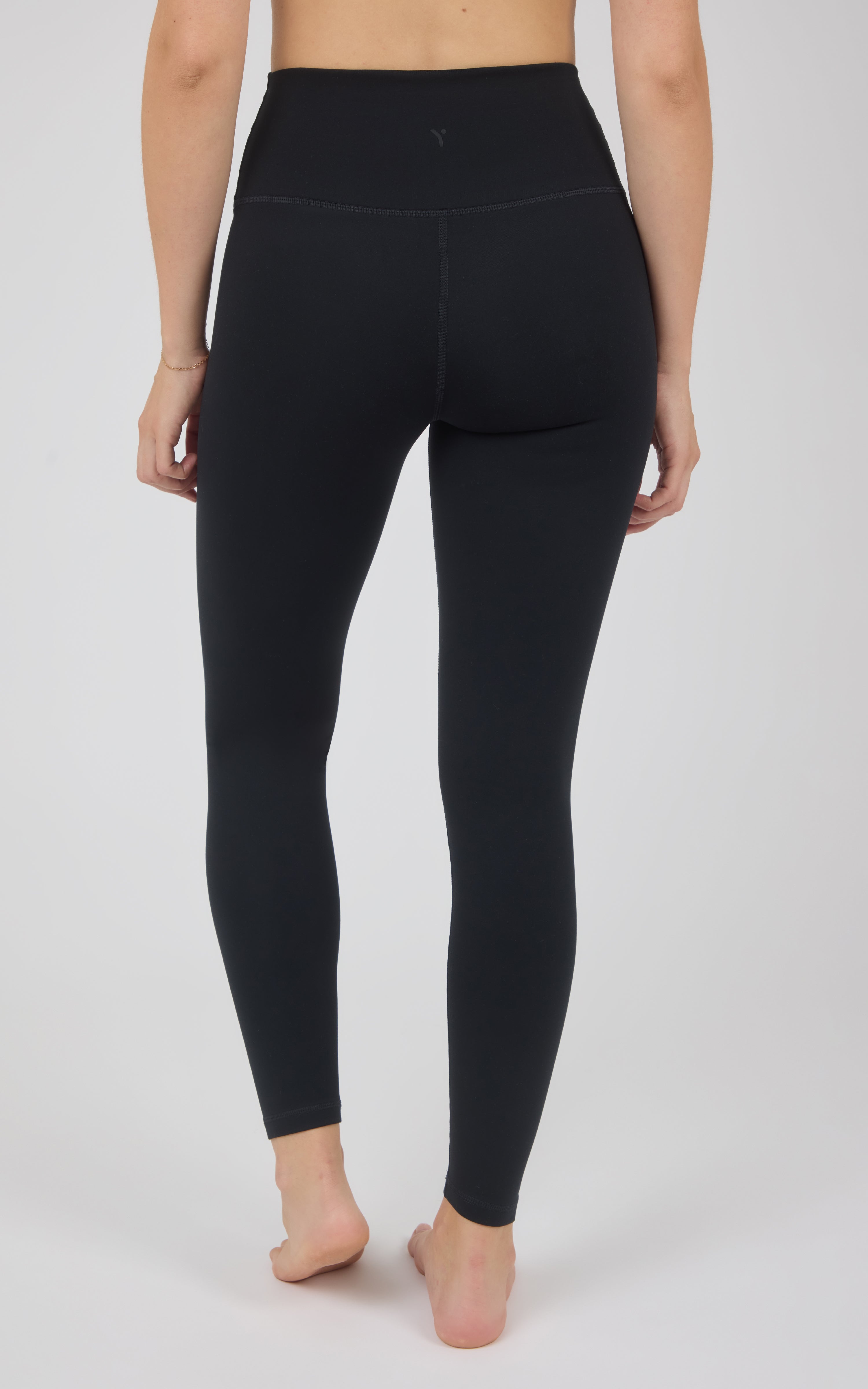 Back view of black high-rise full-length leggings with a smooth, close-fitting silhouette and ankle-length hems.