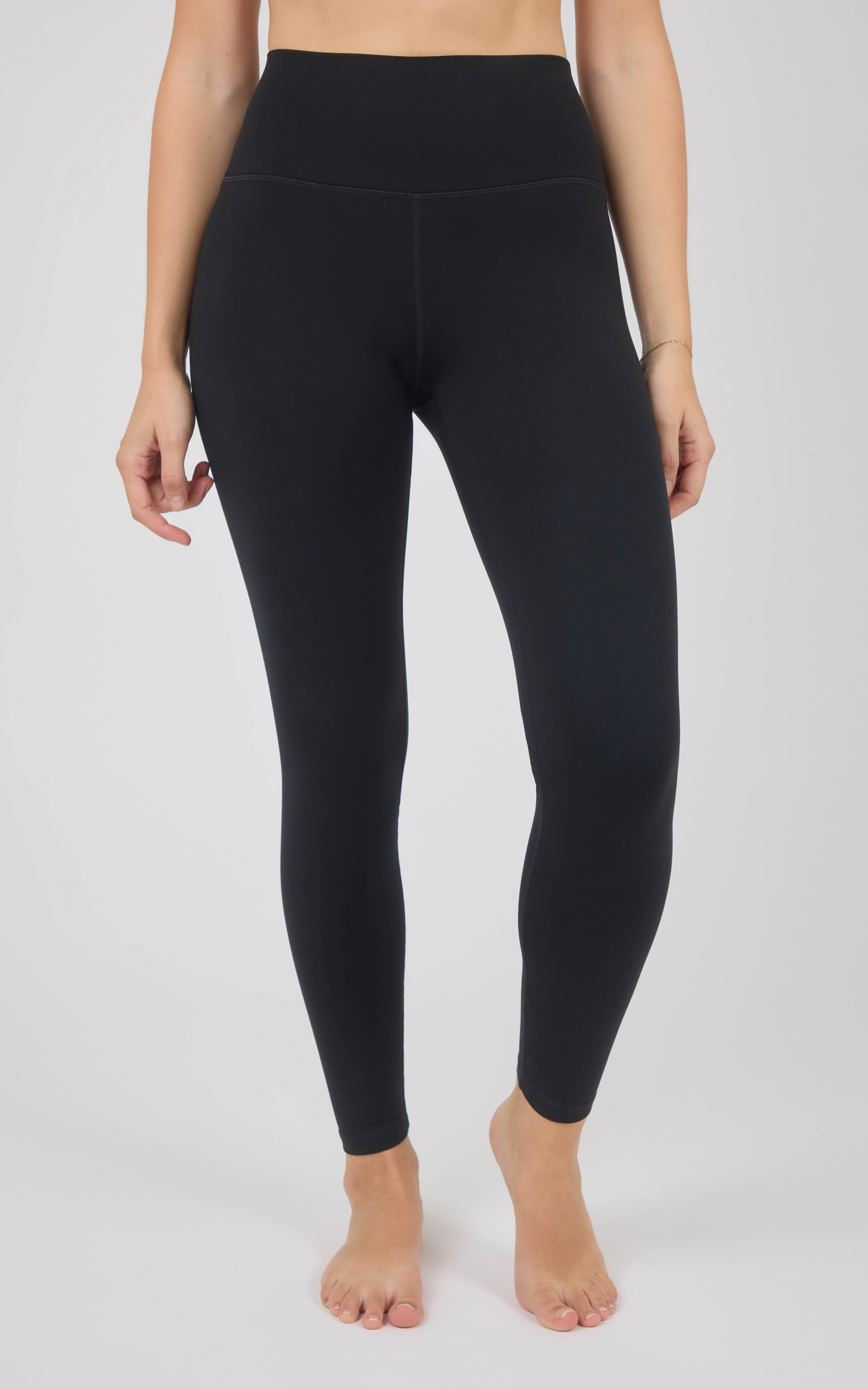 Black full-length high-rise leggings with a smooth, snug fit and tapered ankles, modeled barefoot.