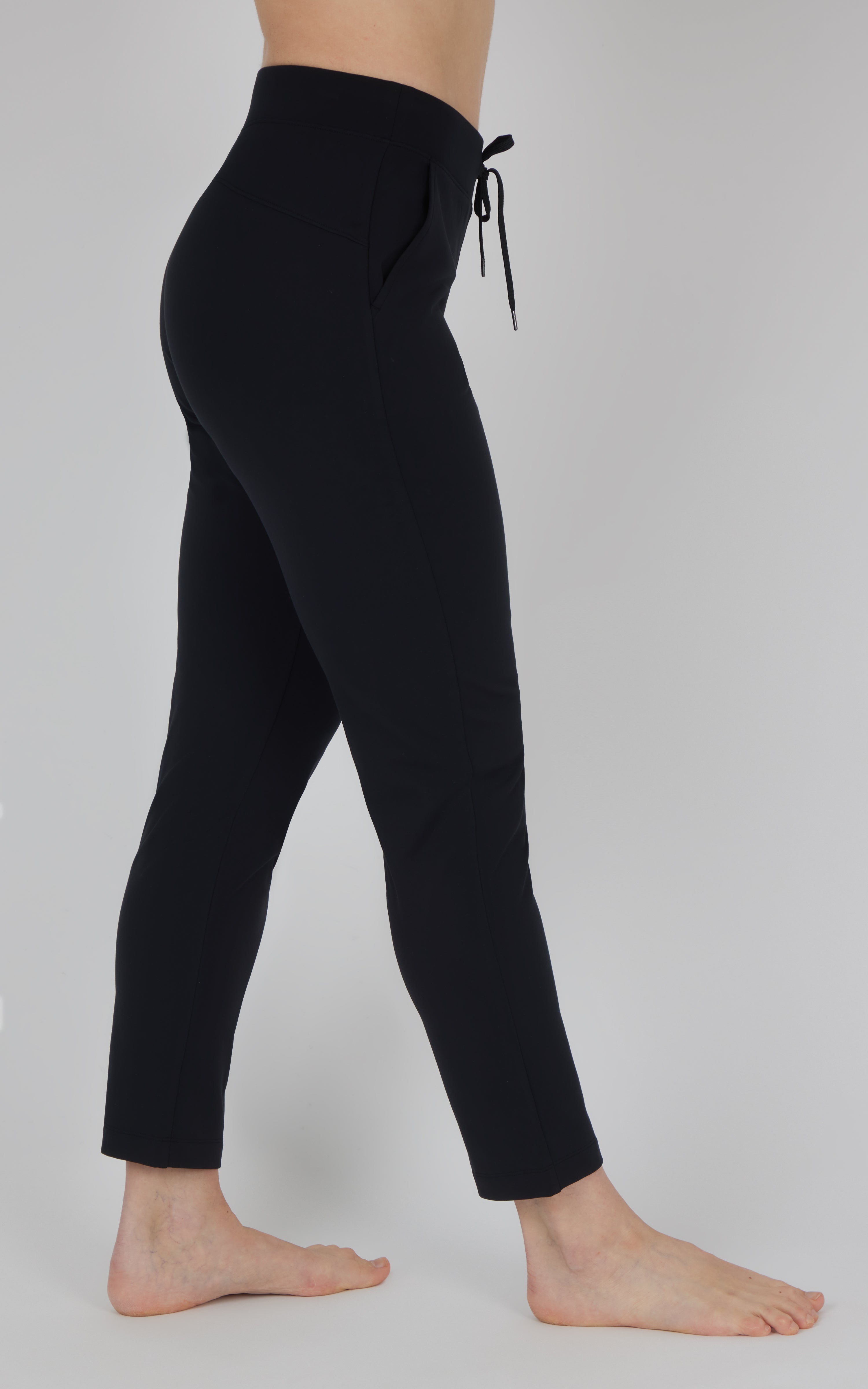 Black fleece straight-leg pants with a slim ankle-length fit, shown on a model from the side.
