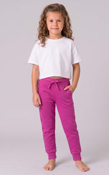Girl wearing bright pink tapered jogger pants with a drawstring waist and side pockets.