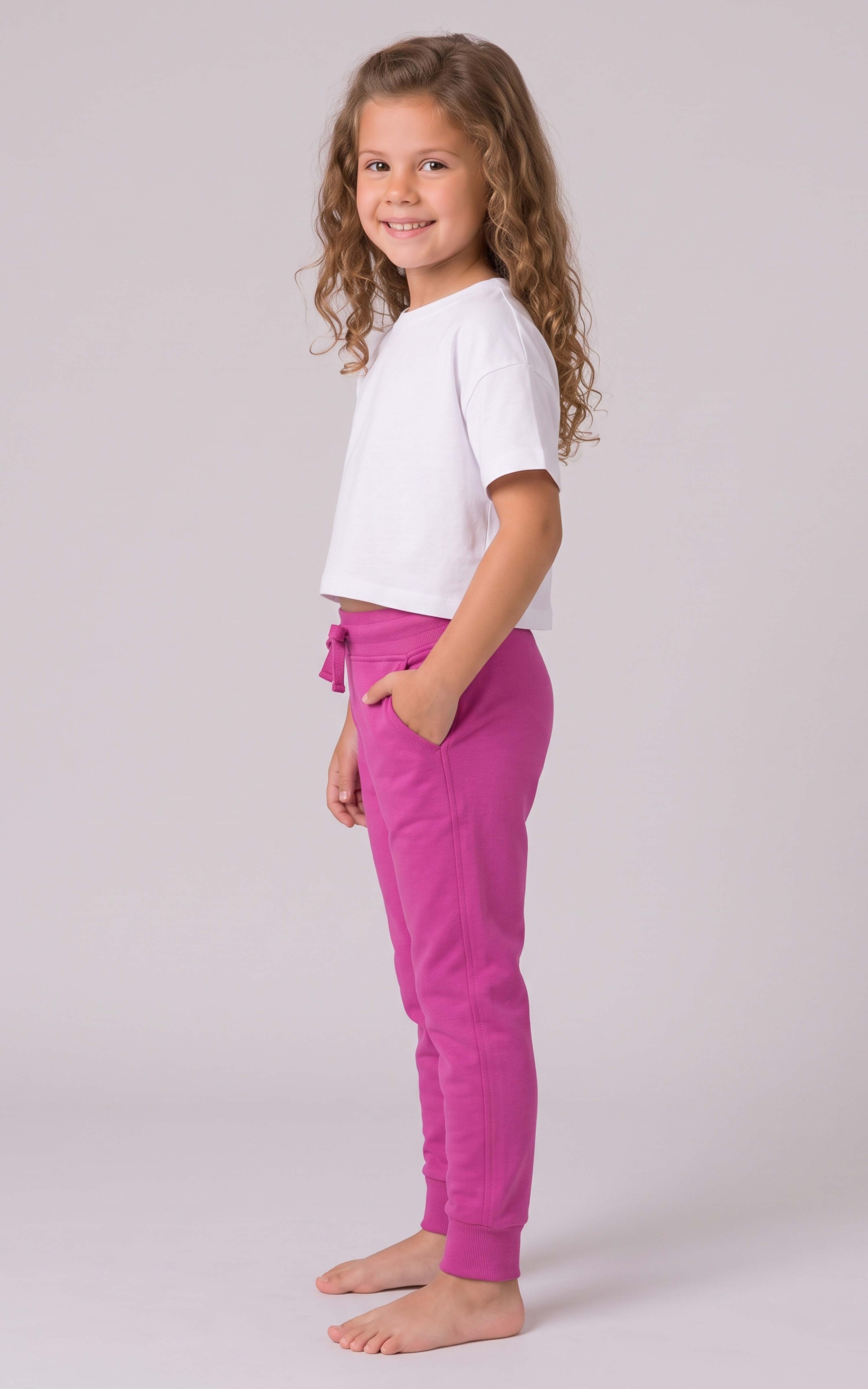Girl wearing bright pink tapered joggers with a drawstring waist and side pockets, paired with a white T-shirt.