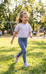 Little girl wearing full-length navy leggings with a white T-shirt and colorful sneakers in a sunny park.