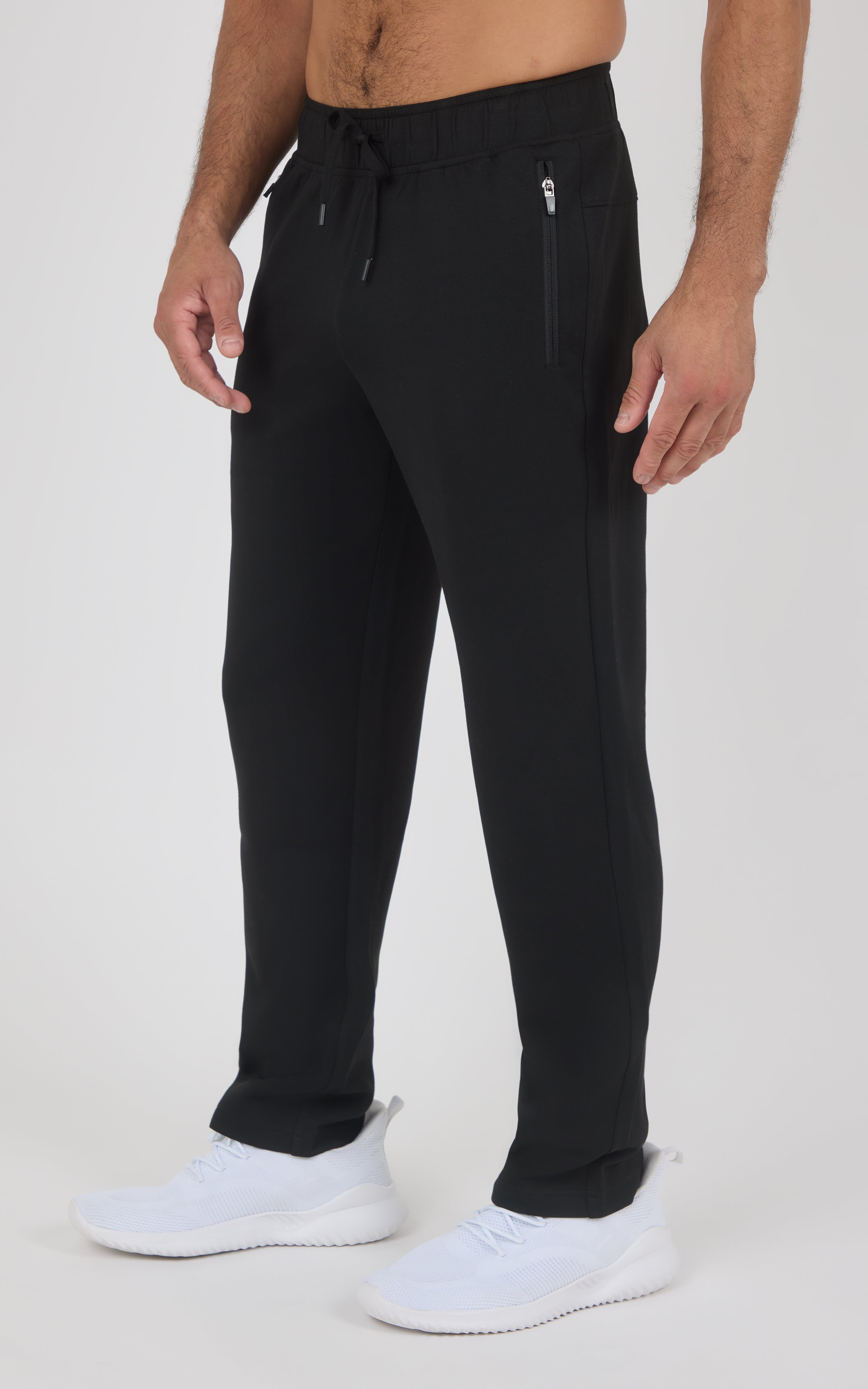 Men's black straight-leg pants with drawstring waist and zippered side pockets, worn with white sneakers.