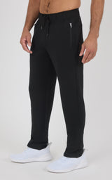 Men's black straight-leg pants with drawstring waist and zippered side pockets, worn with white sneakers.