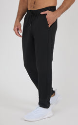 Black tapered men's jogger pants with an elastic drawstring waist, cuffed ankles, and white sneakers.