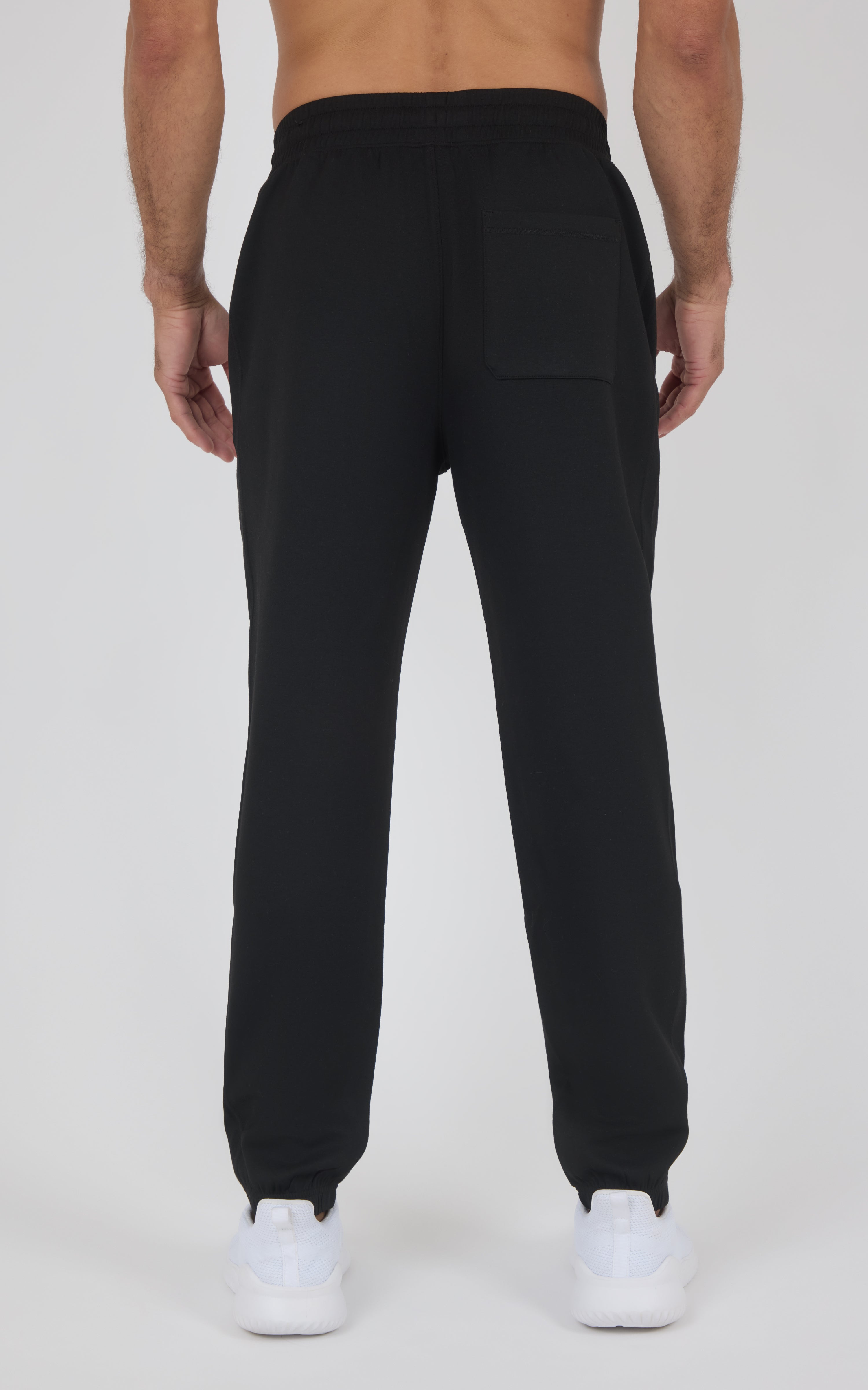 Black tapered jogger pants with an elastic waistband and cuffs, worn with white sneakers.