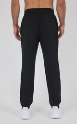 Black tapered jogger pants with an elastic waistband and cuffs, worn with white sneakers.