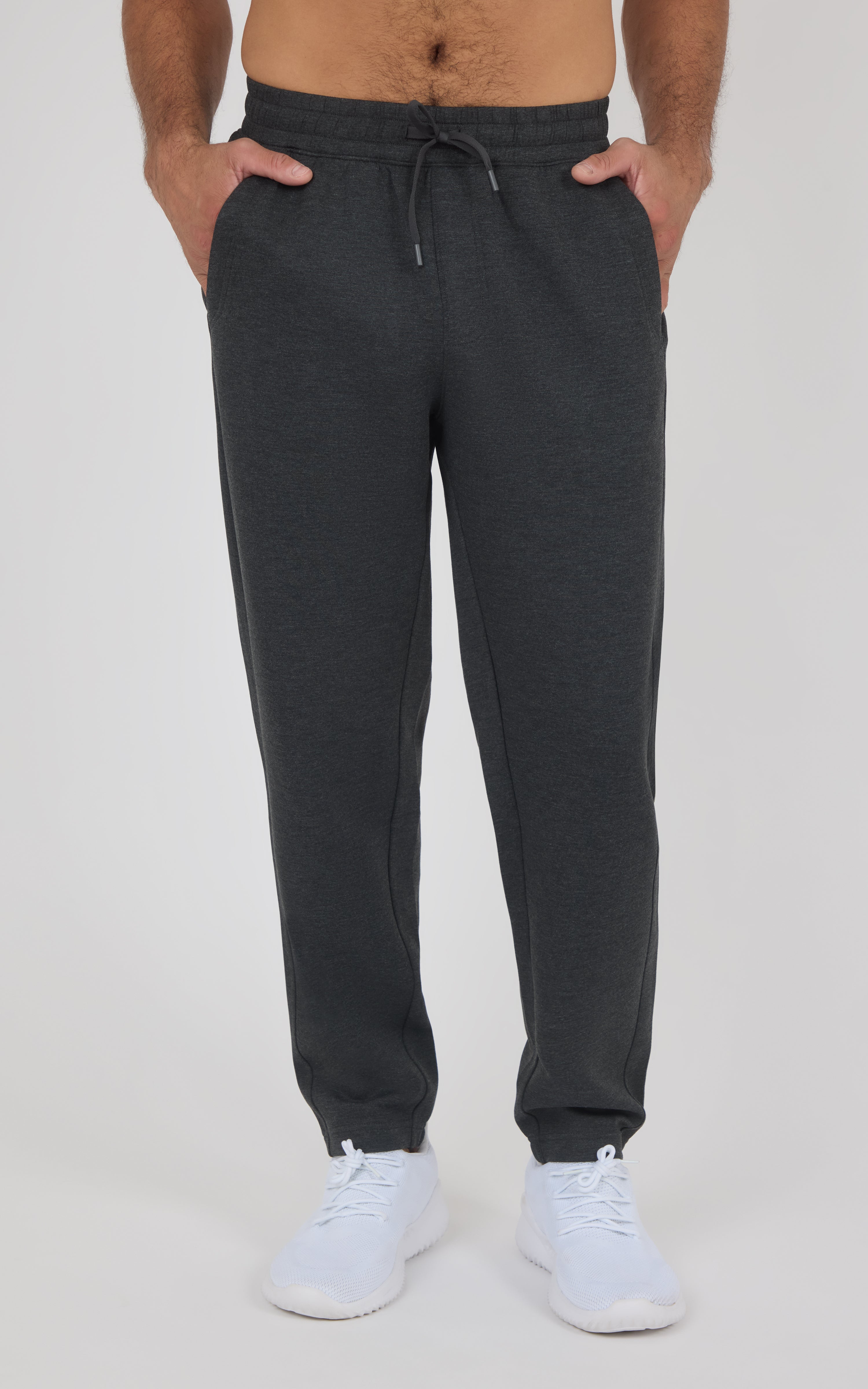Men’s charcoal joggers with a drawstring waist, tapered legs, side pockets, and elastic cuffs, styled with white sneakers.