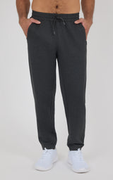 Men’s charcoal joggers with a drawstring waist, tapered legs, side pockets, and elastic cuffs, styled with white sneakers.
