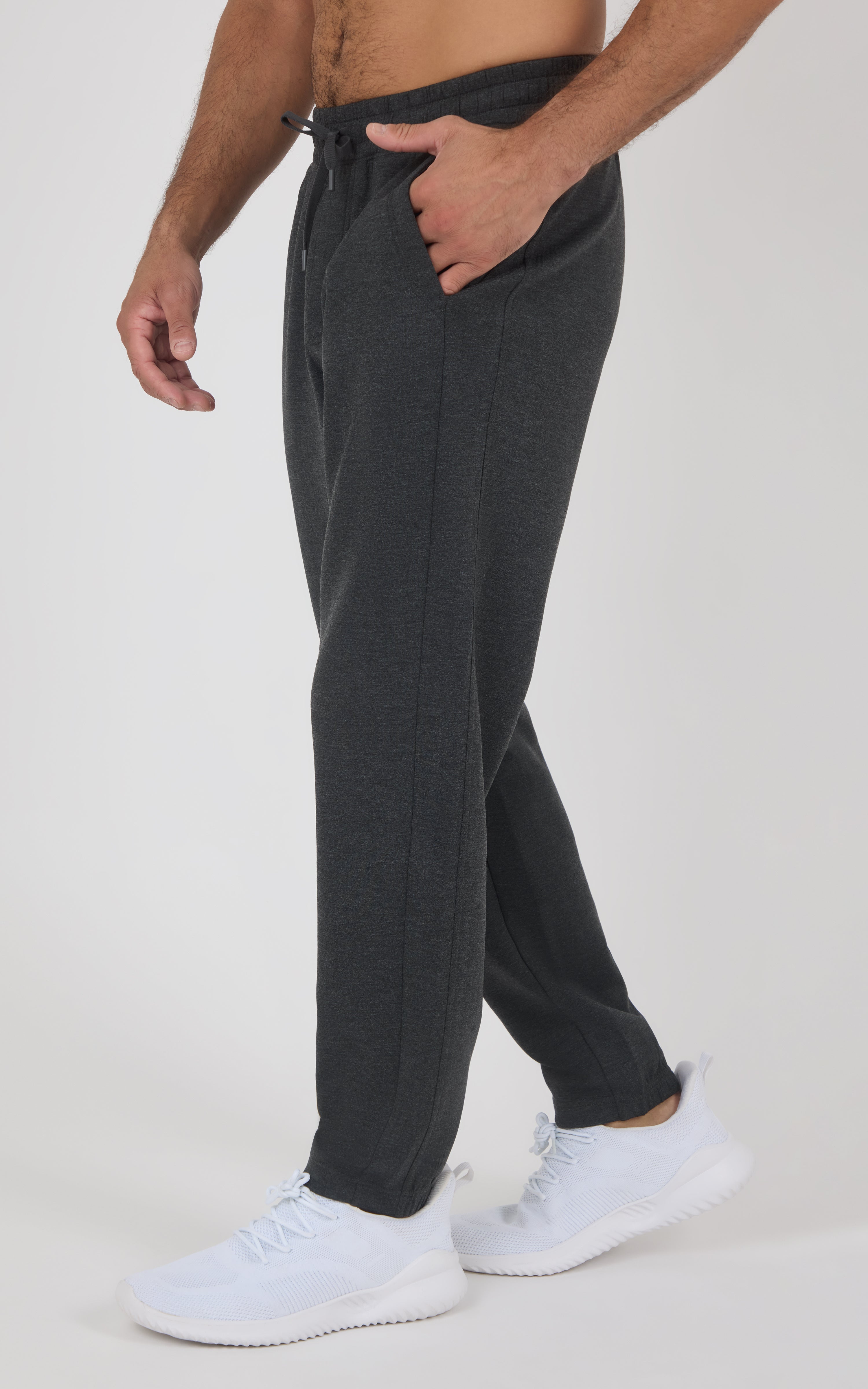 Men’s charcoal gray joggers with a relaxed tapered fit, elastic drawstring waist, side pockets, and white sneakers.