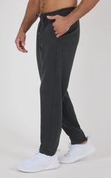 Men’s charcoal gray joggers with a relaxed tapered fit, elastic drawstring waist, side pockets, and white sneakers.