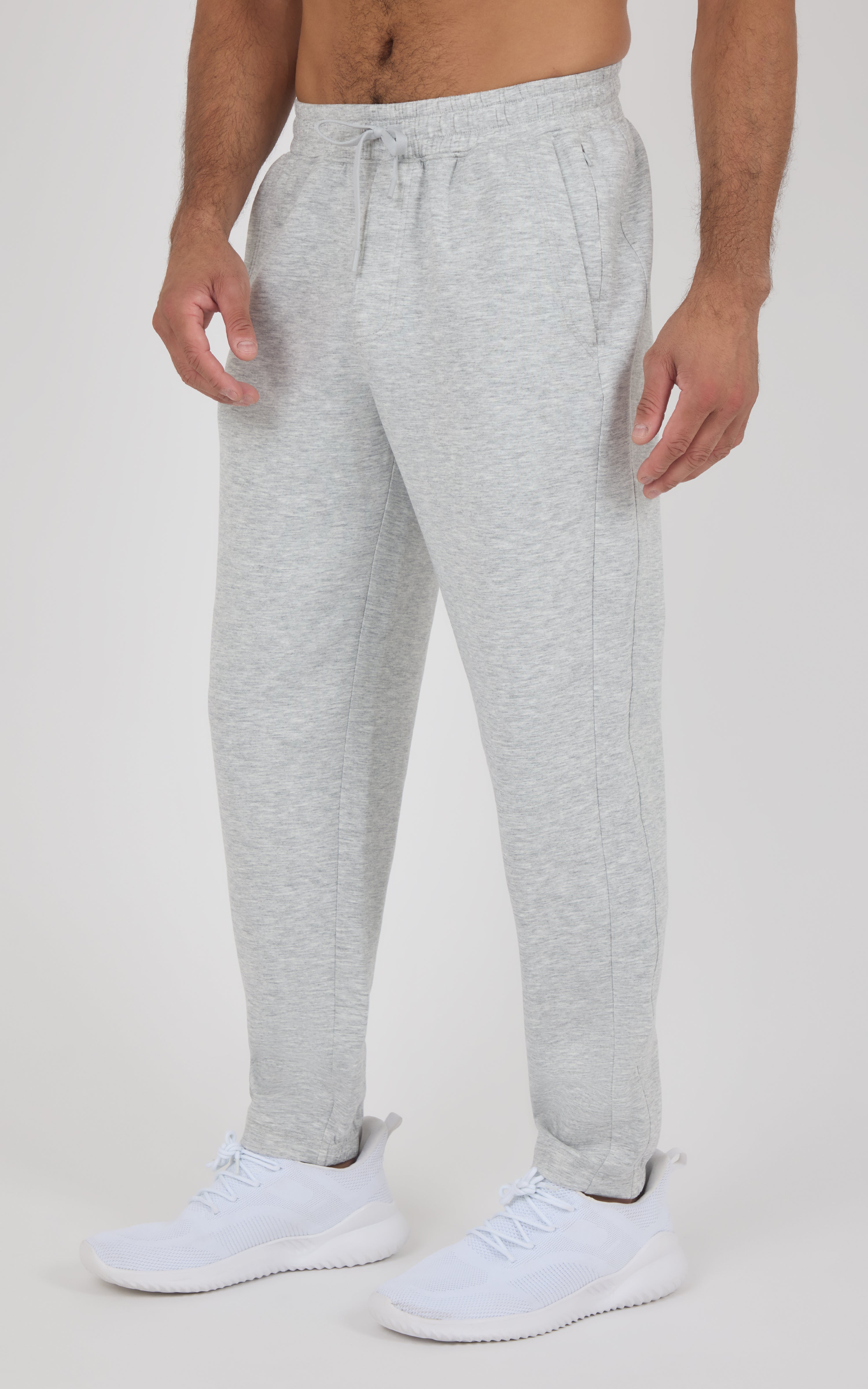 Light gray soft joggers with an elastic drawstring waist, tapered legs, and cuffed ankles, styled with white sneakers.