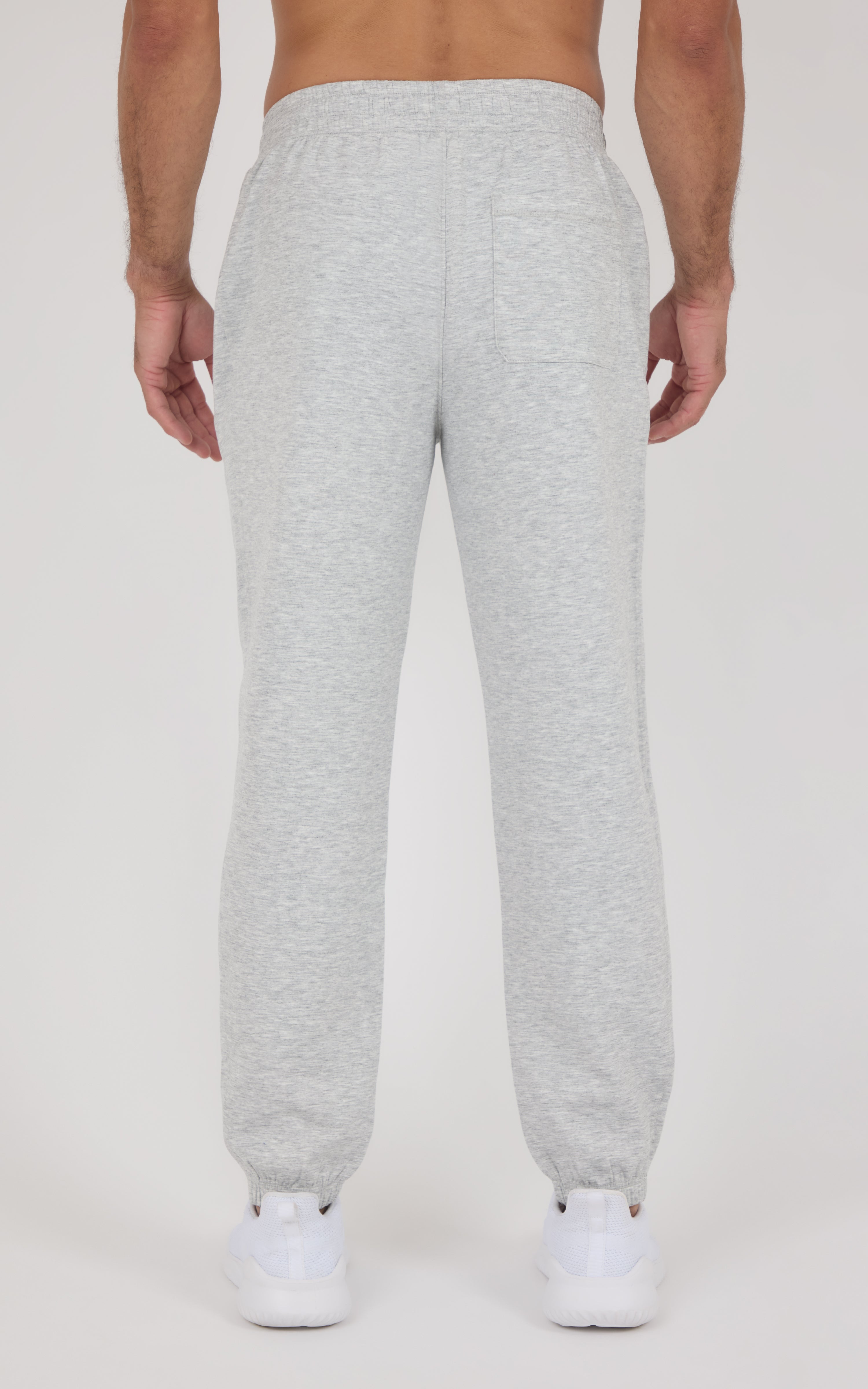 Light gray tapered joggers with an elastic waistband and cuffs, shown from the back with white sneakers.