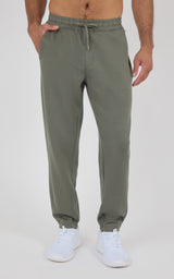 Men’s soft gray-green joggers with a drawstring waist, tapered legs, elastic cuffs, and white sneakers.