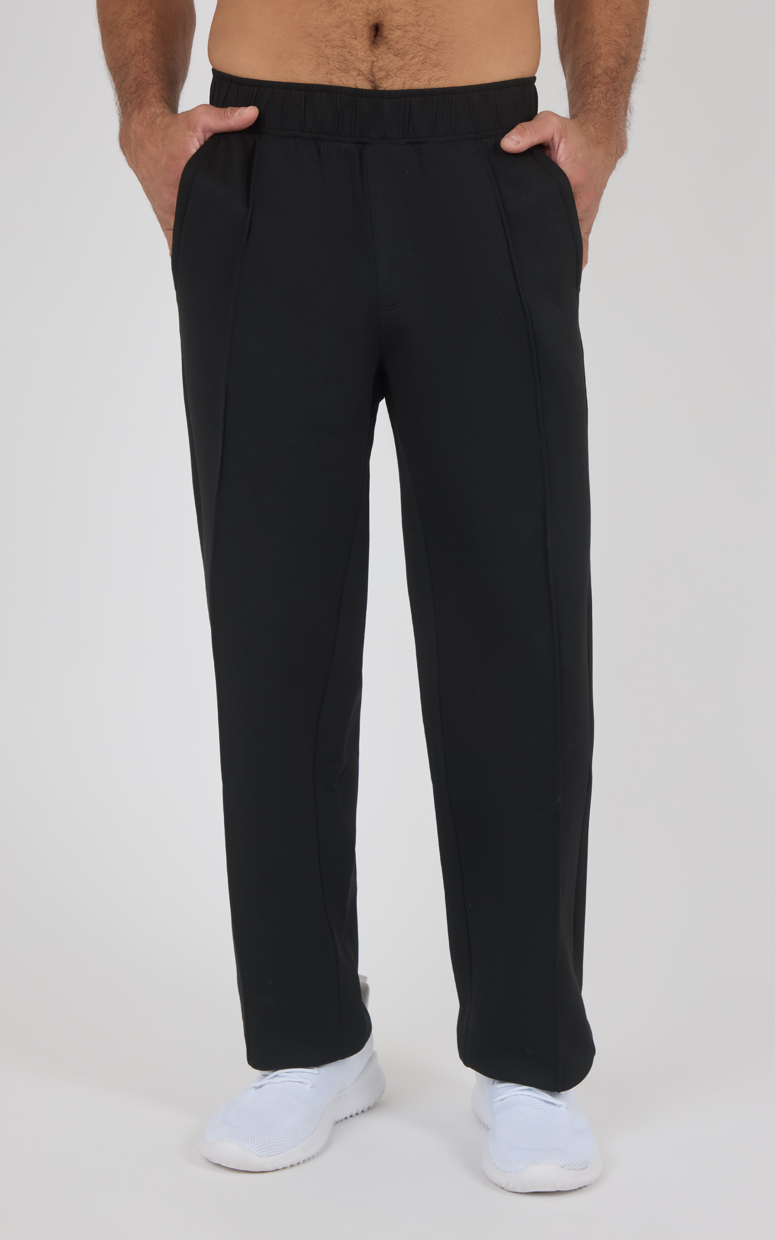 Black straight-leg pants with a soft, smooth fabric, elastic waistband, and side pockets worn with white sneakers on a light