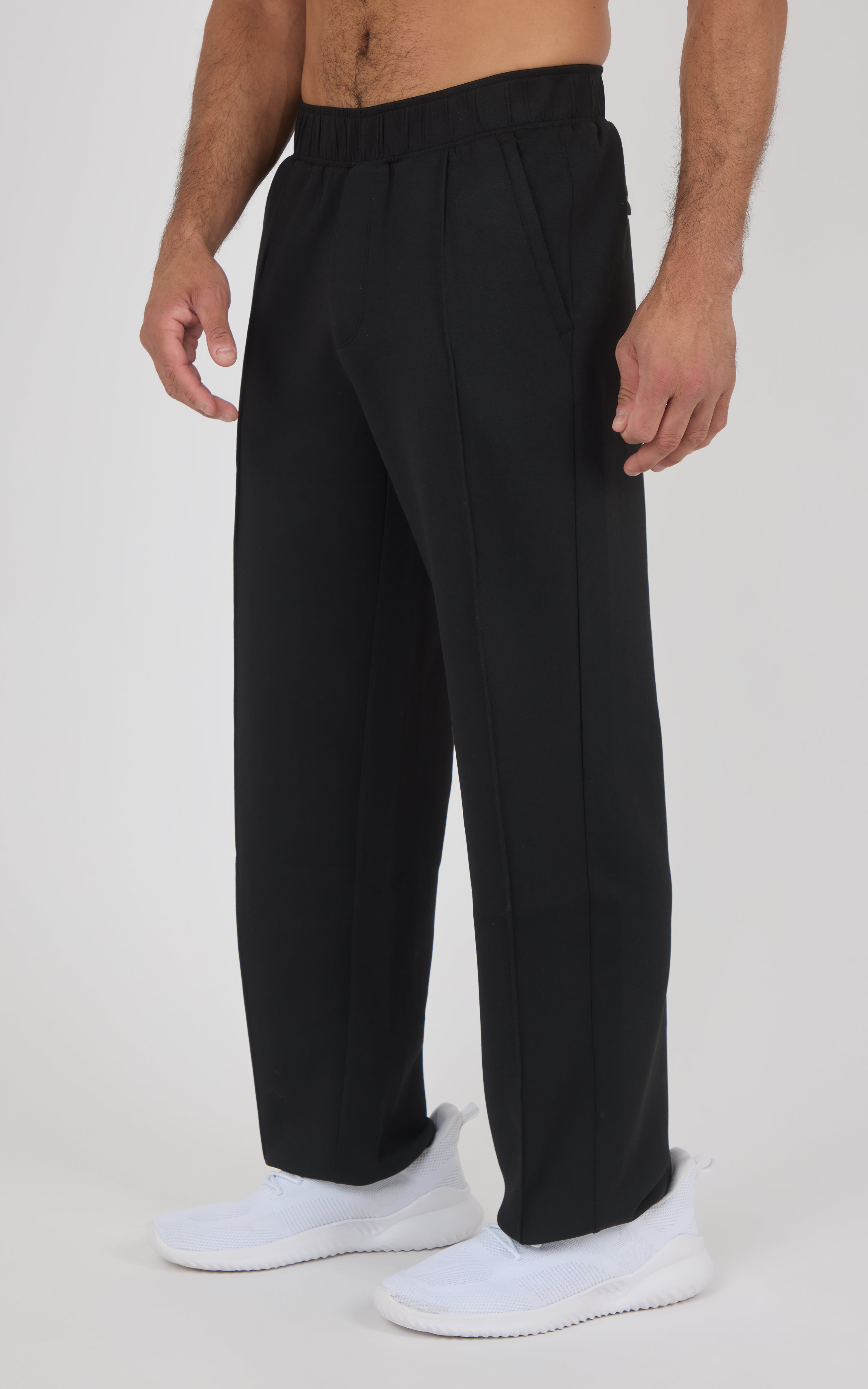 Black straight-leg pants with soft fabric, elastic waistband, slightly loose fit, worn with white sneakers.