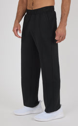 Black straight-leg pants with soft fabric, elastic waistband, slightly loose fit, worn with white sneakers.