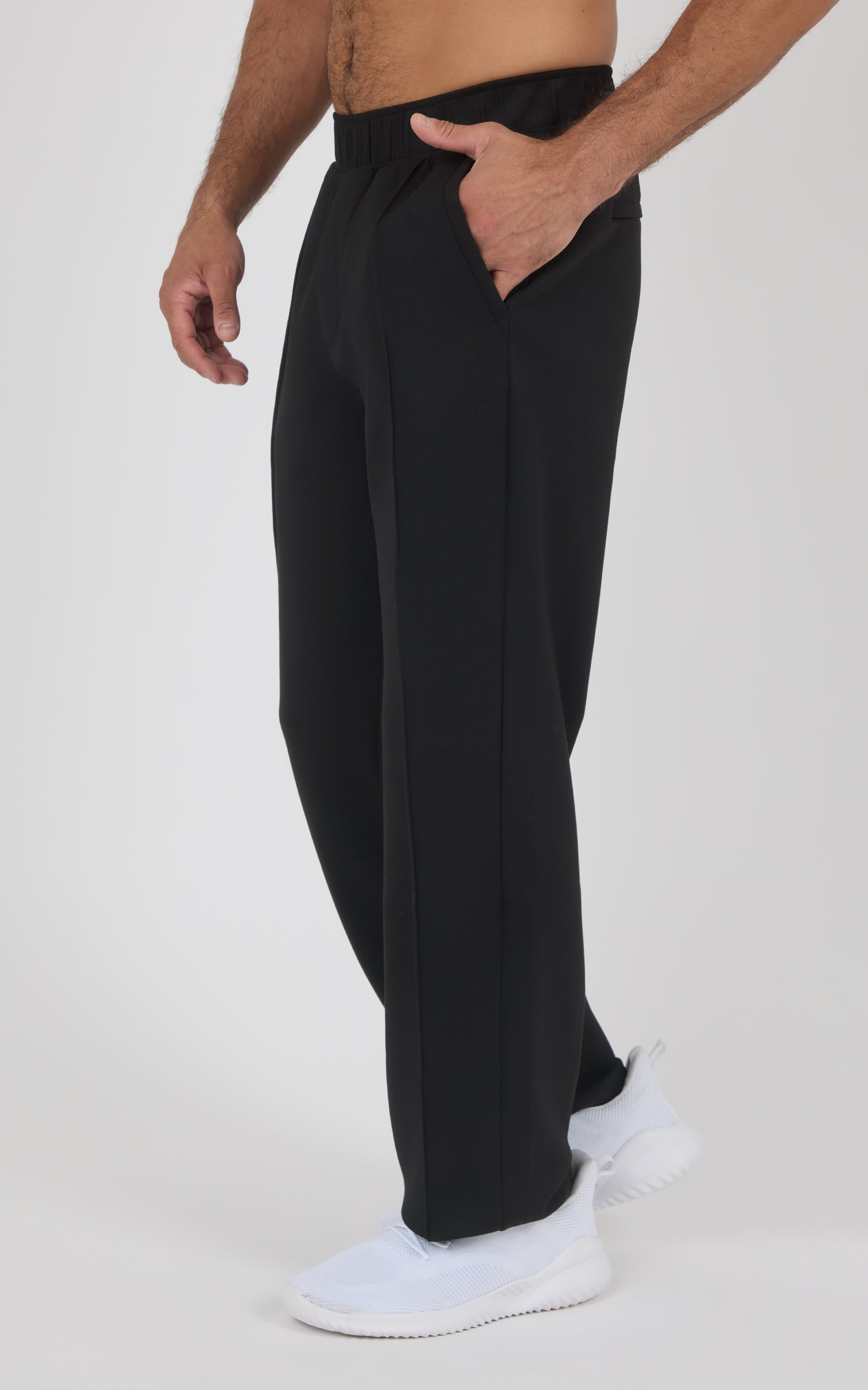 Men's black straight-leg pants with a soft matte finish, elastic waistband, side pockets, and relaxed fit worn with white.