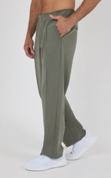 Olive green straight-leg pants with a soft, lightweight fabric, featuring an elastic waistband and side pockets, worn with.