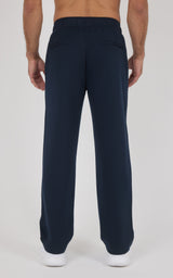 Navy blue straight-leg pants with a smooth fabric and elastic waistband worn by a standing male model facing away.