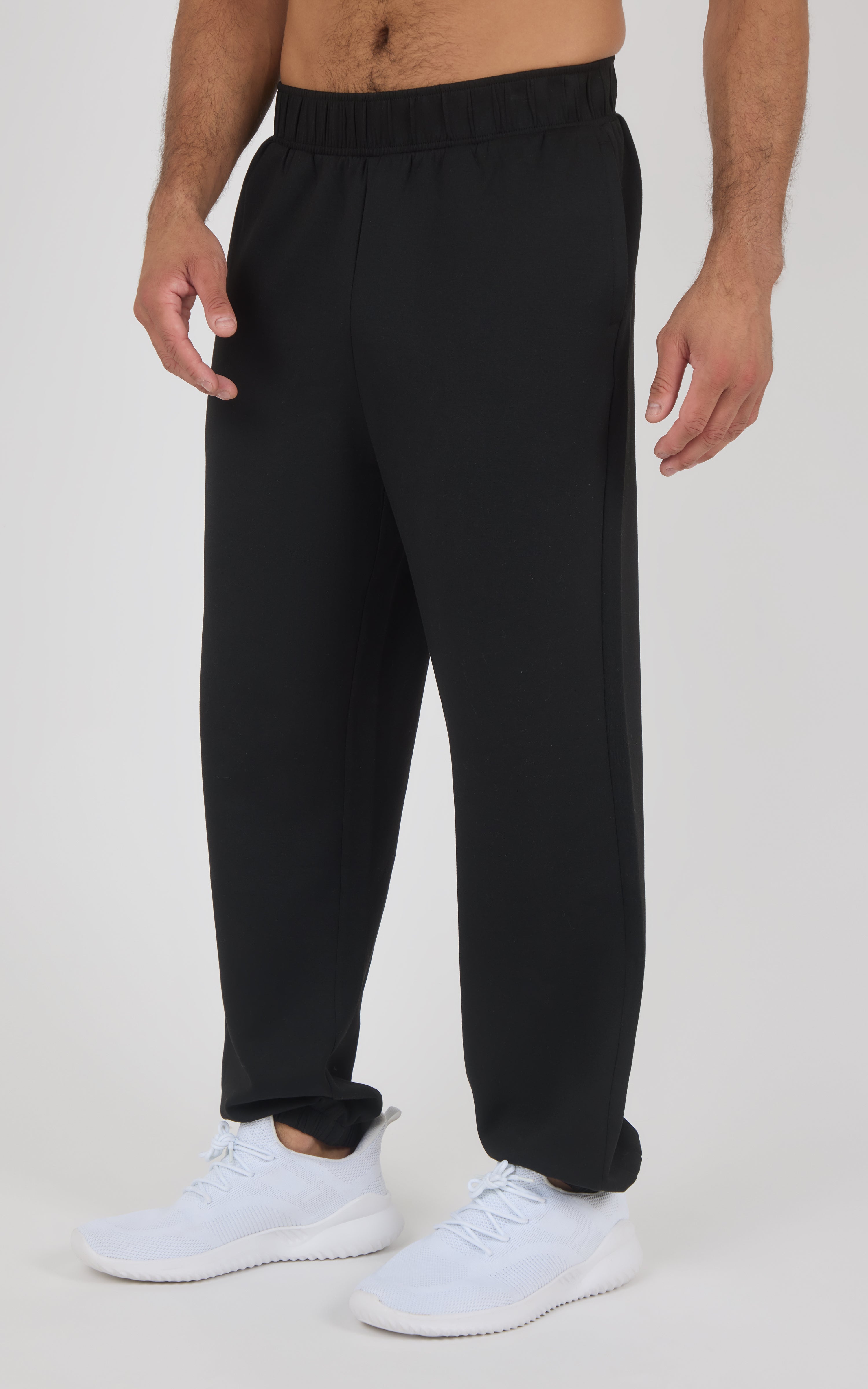 Black jogger pants with elastic waistband and cuffs, loose fit, worn with white sneakers.