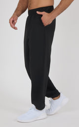 Black soft fabric jogger pants with elastic waistband and side pockets, worn with white sneakers.