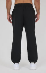 Black men's jogger pants with elastic waistband and cuffs, made from soft lightweight fabric, shown from the back.