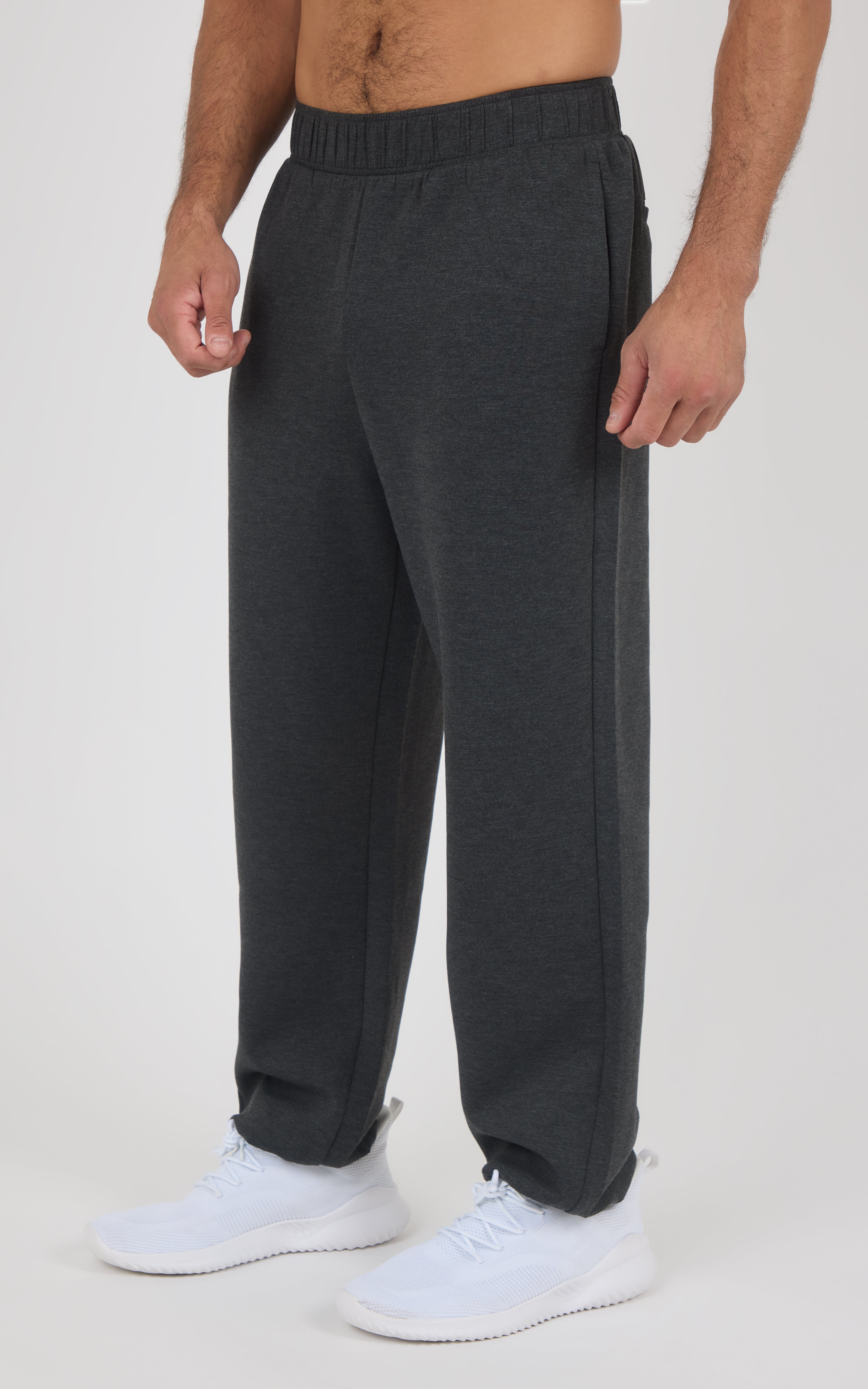 Charcoal gray soft fabric joggers with elastic waistband and relaxed fit, worn with white sneakers.