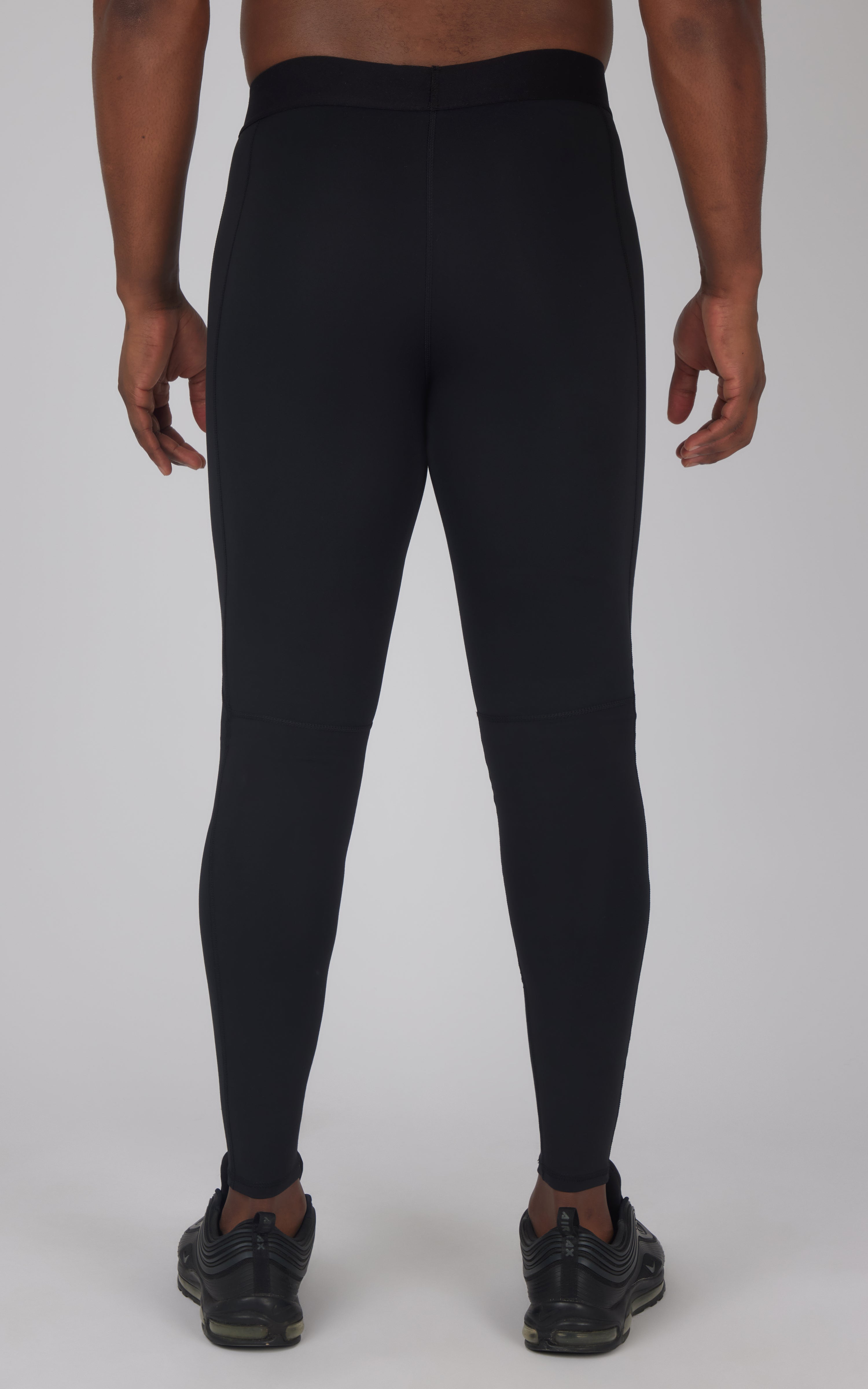 Black slim-fit men's running tights with high waistband and ankle cuffs, shown from back.