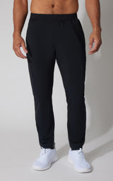 Black tapered joggers with an elastic waistband, side pockets, ankle-length cuffs, and a smooth stretch fabric, styled with.