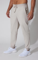 Men's light beige tricot joggers with drawstring waist and tapered legs.
