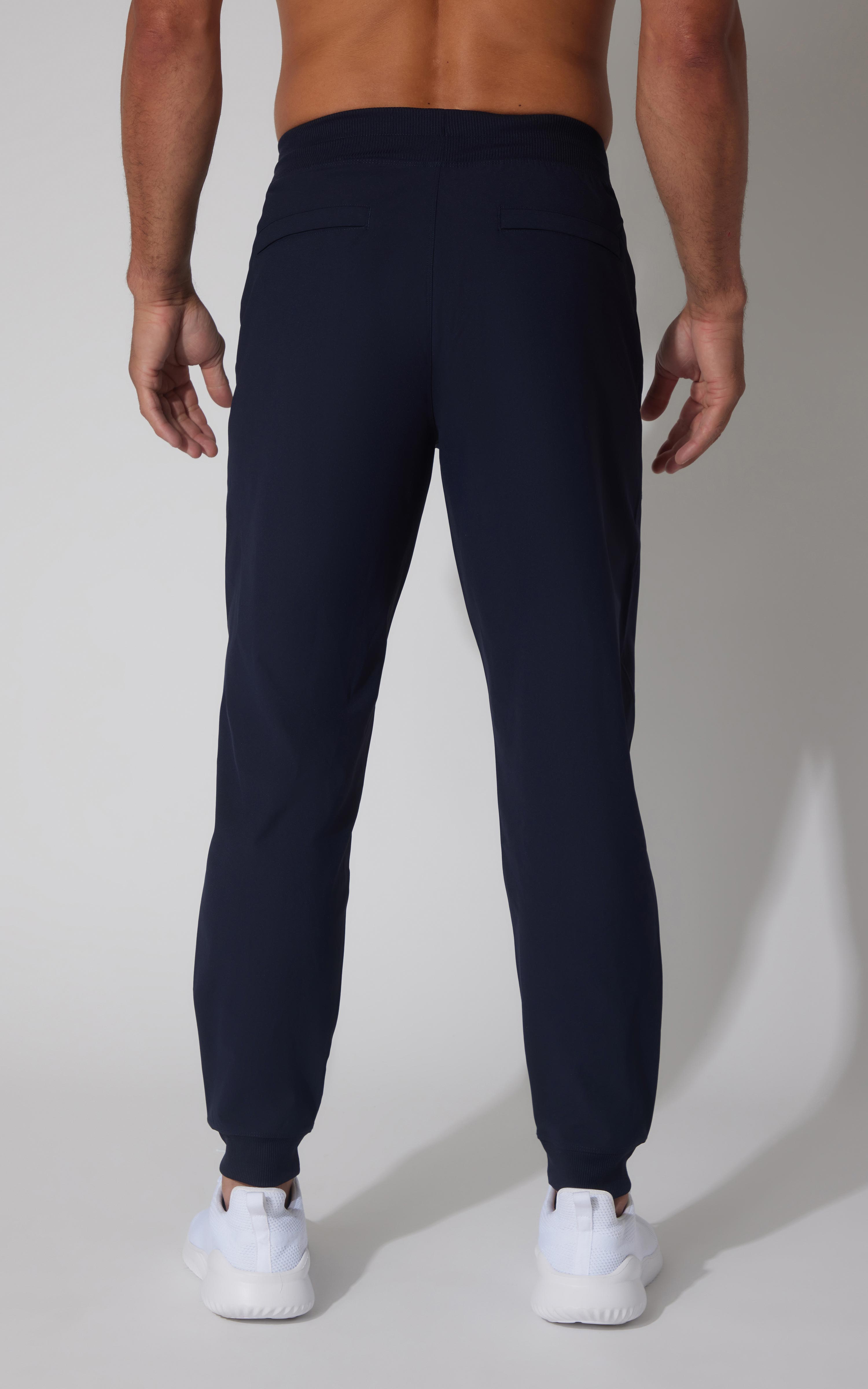 Men's jogger pants in true navy with elastic cuffs and a slim fit back view.
