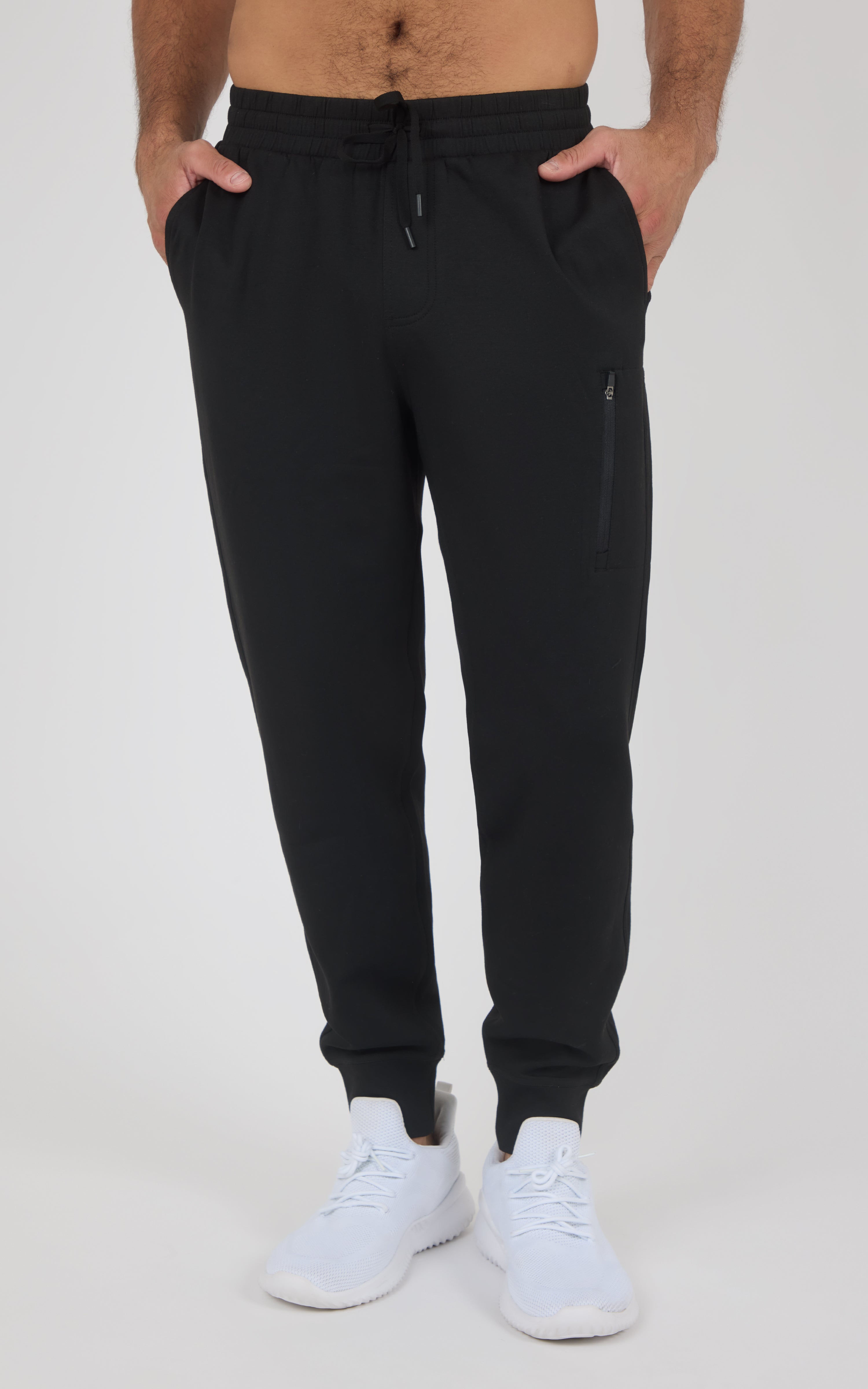 Black tapered jogger pants with elastic cuffs, drawstring waistband, side pockets, and zippered pocket on thigh, worn with.
