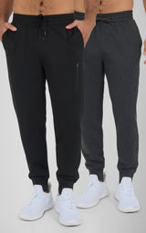 Two men's joggers in black and dark gray, made of soft, lightweight fabric, with elastic waistbands and ankle cuffs, styled.