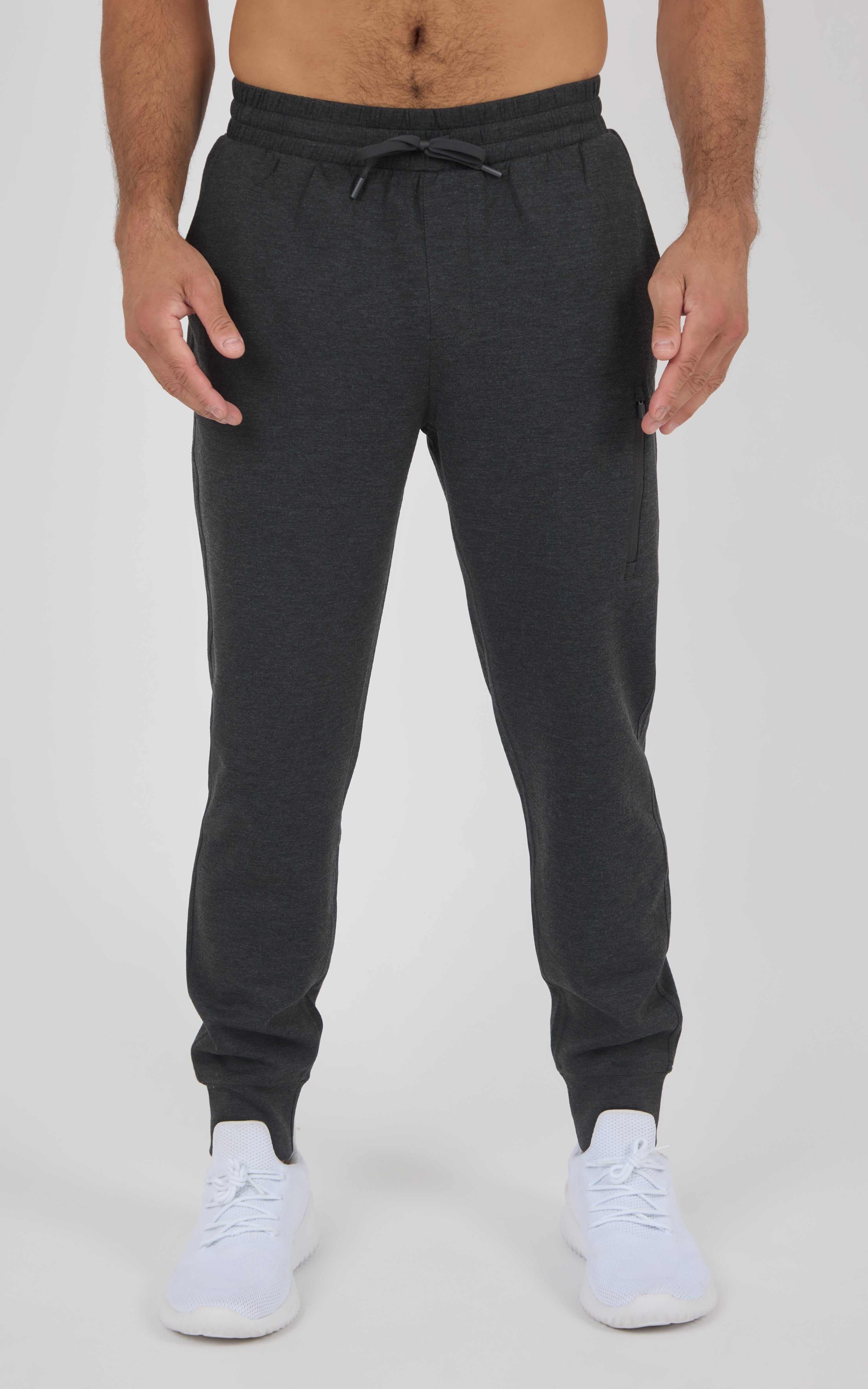 Charcoal gray joggers with elastic waistband, adjustable drawstring, tapered legs, and cuffed ankles, worn with white.
