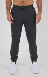 Charcoal gray joggers with elastic waistband, adjustable drawstring, tapered legs, and cuffed ankles, worn with white.