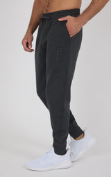 Black tapered jogger pants with side pockets and elastic cuffs, worn with white sneakers and a drawstring waistband.