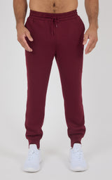 Men's jogger pants in deep burgundy with elastic cuffs, drawstring waistband, and soft, smooth fabric, styled for active.