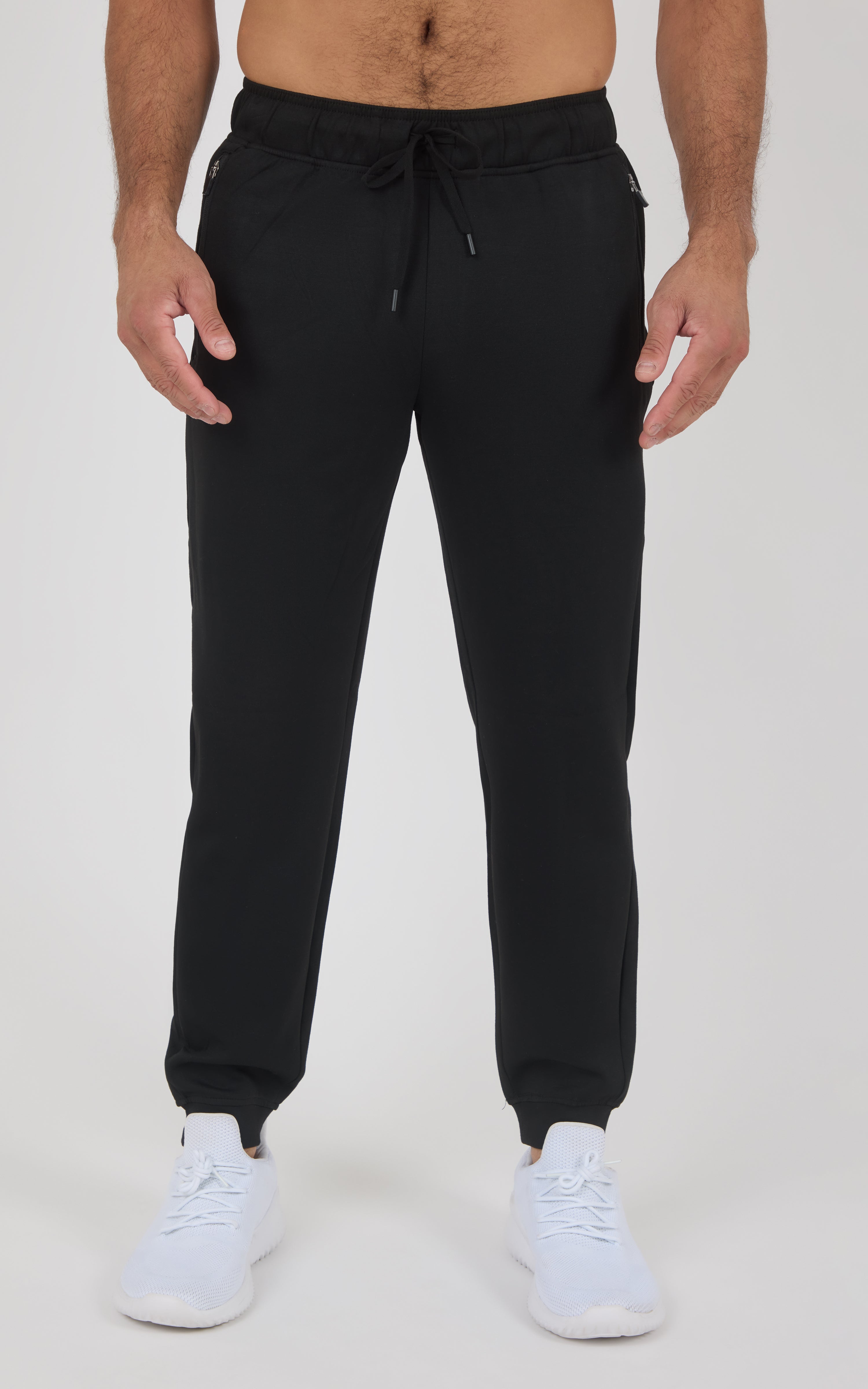 Black men’s jogger pants with a tapered fit, elastic cuffs, drawstring waist, and white sneakers.