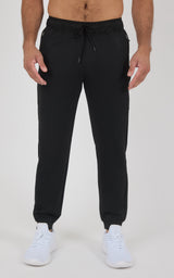 Black men’s jogger pants with a tapered fit, elastic cuffs, drawstring waist, and white sneakers.