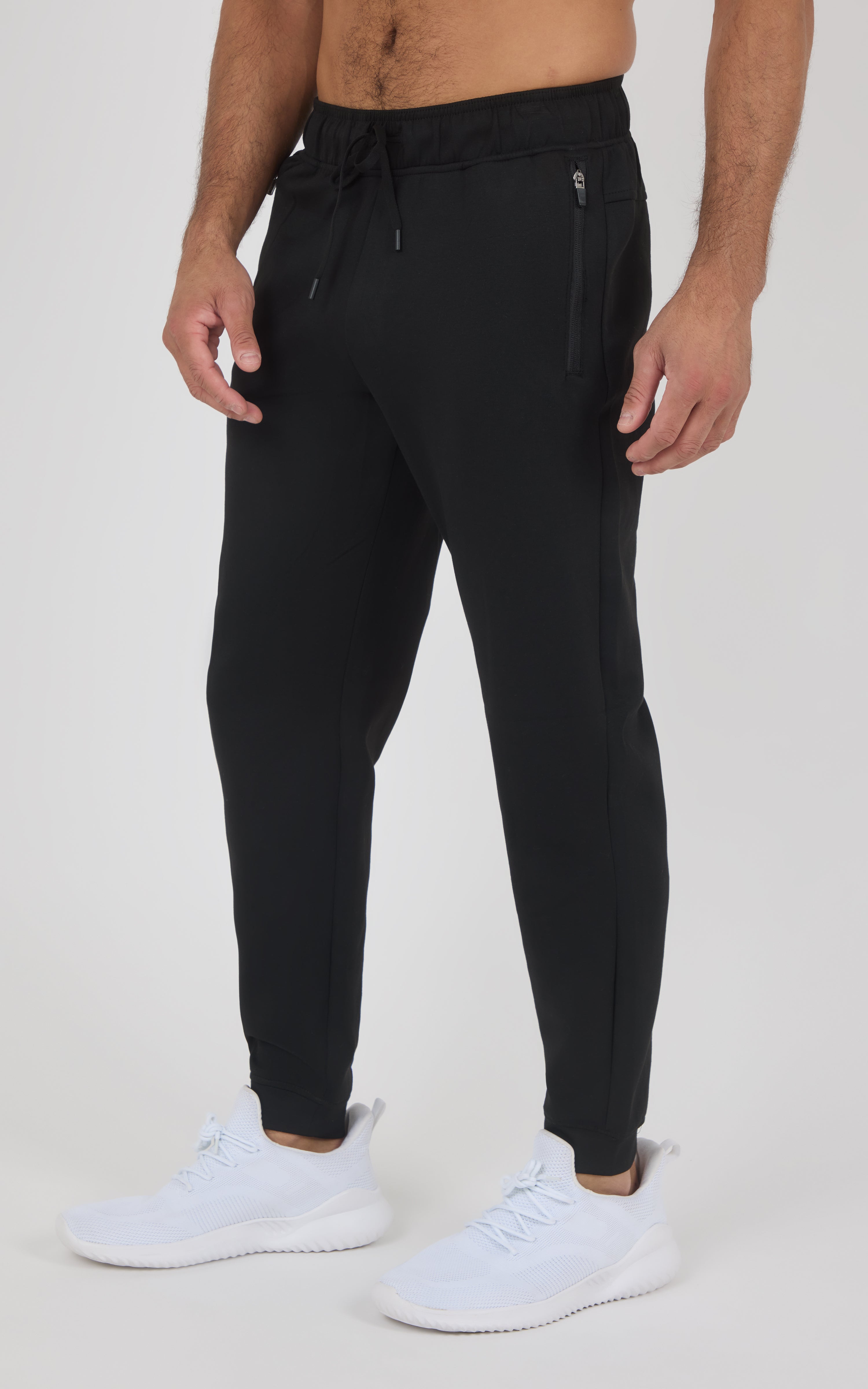 Black tapered jogger pants with a drawstring waist, side pockets, and elastic cuffs, worn with white sneakers.