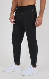 Black tapered jogger pants with a drawstring waist, side pockets, and elastic cuffs, worn with white sneakers.