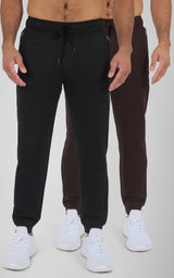 Black and dark brown men's joggers with elastic waistbands, tapered legs, and white sneakers.