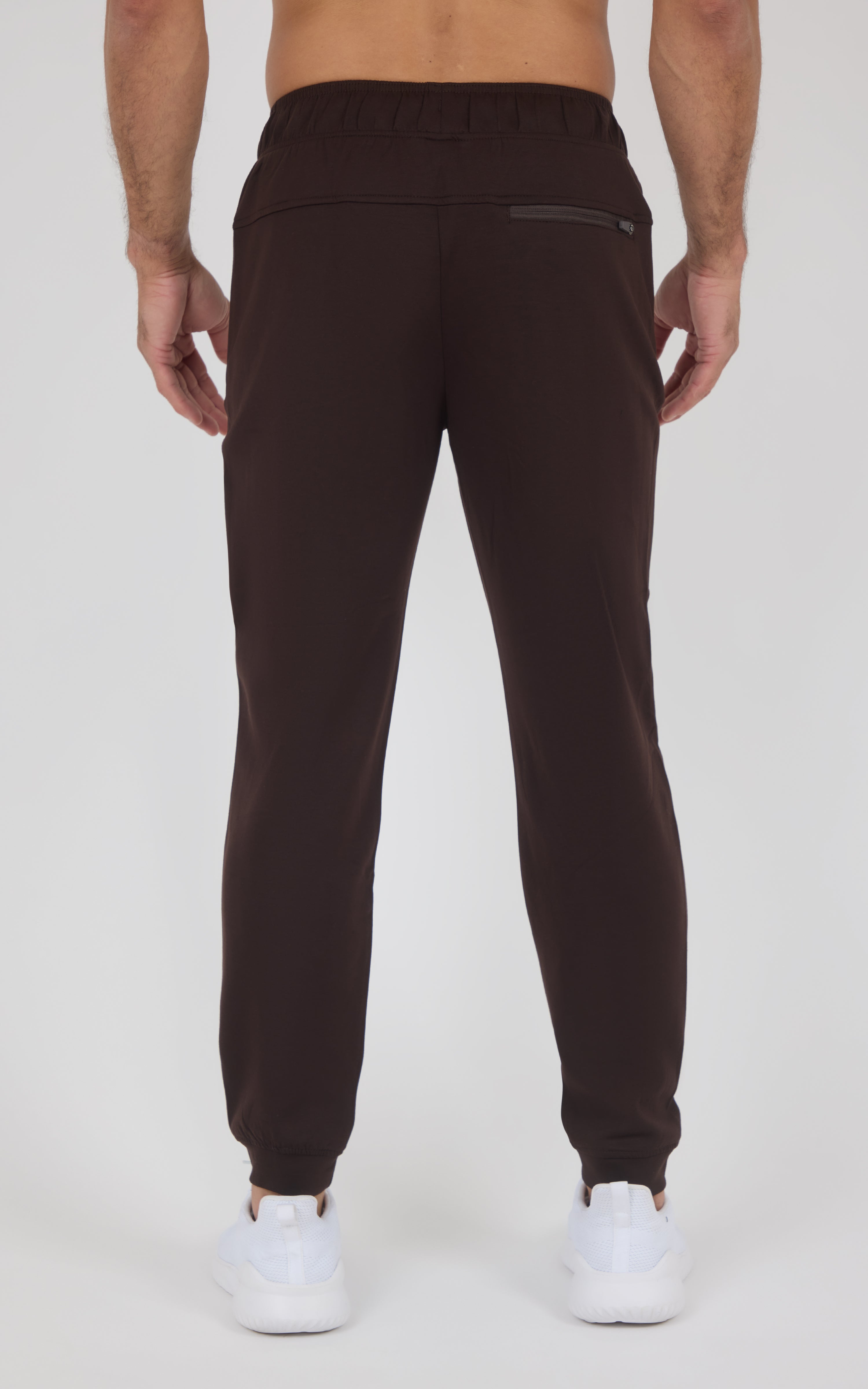 Dark brown men’s jogger pants with a tapered fit, elastic cuffs, and a back pocket, shown from behind.